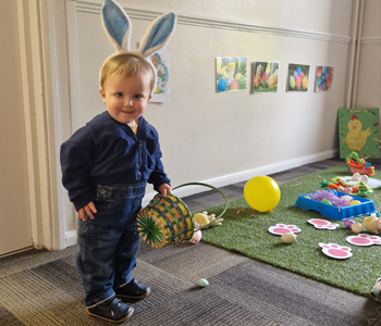 Child wearing bunny ears and holding a basket